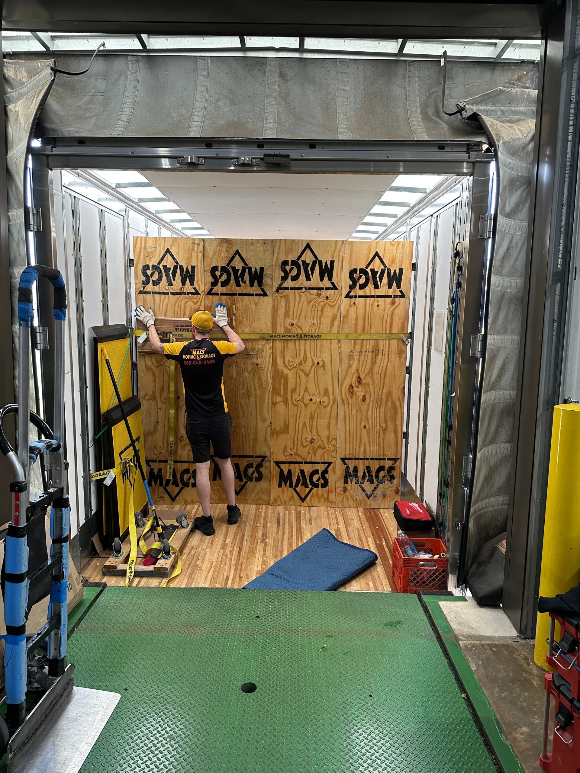 MACs Moving and Storage mover building a branded plywood storage vault inside a long-distance moving truck